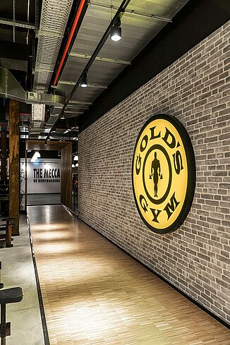 Innenansicht des Fitnesscenters Gold's Gym in Jena mit großem Gold's Gym Logo an der Wand.